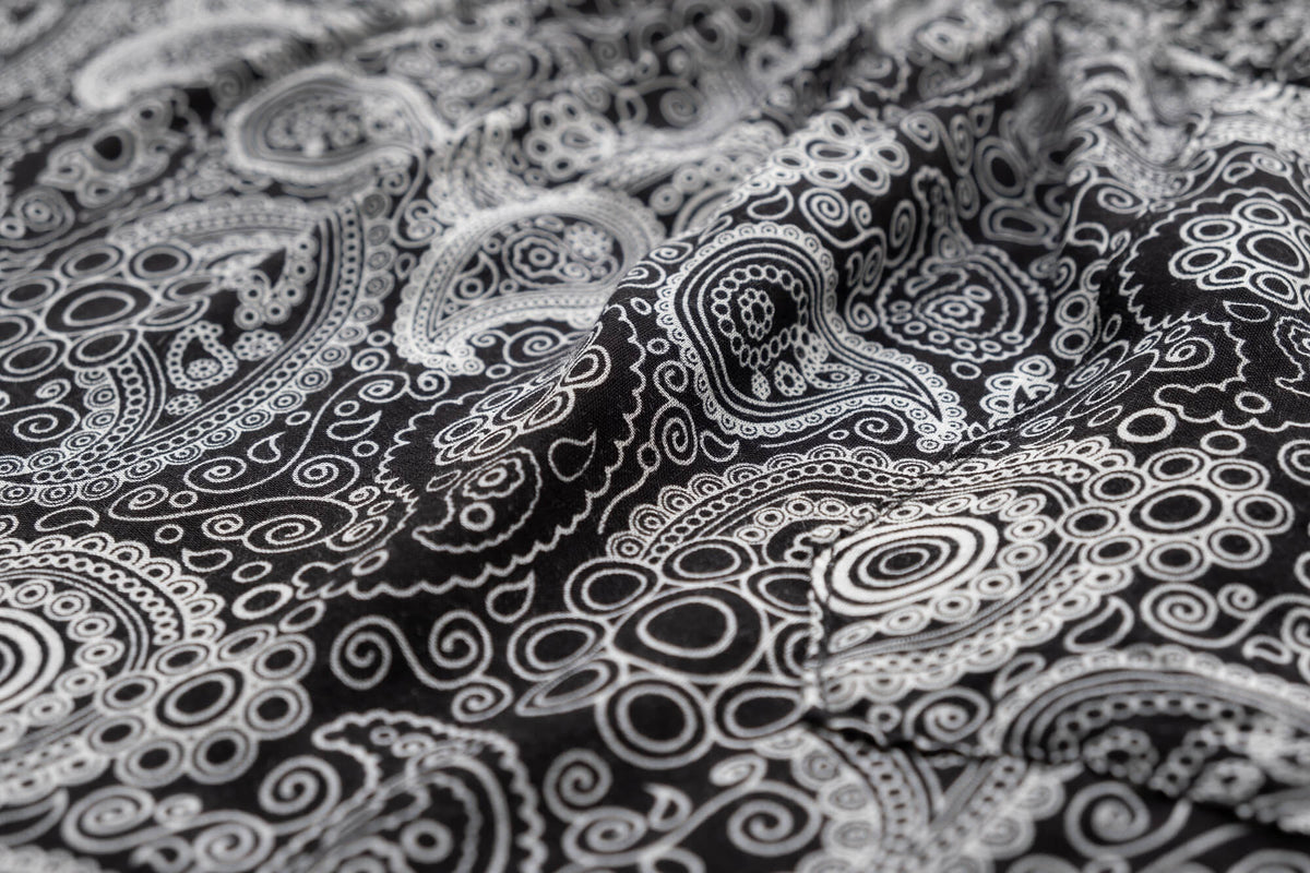 Black paisley rayon flow pants fabric close-up, swirling circular pattern