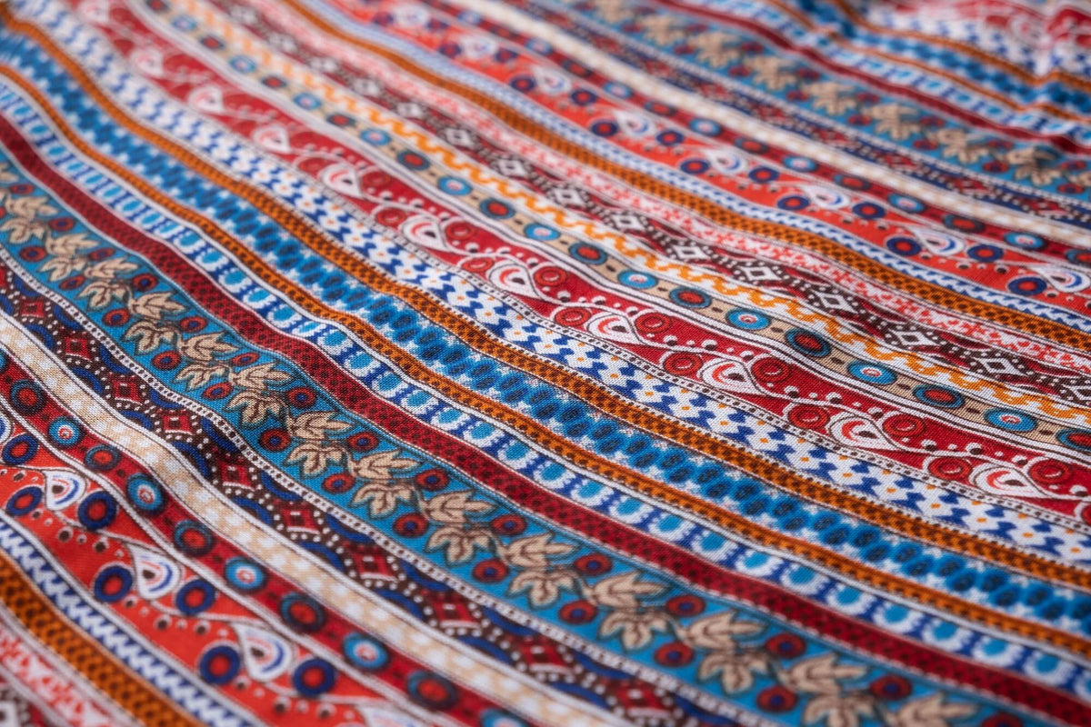 Close-up of red, blue, and white patterned rayon fabric with repeating motifs