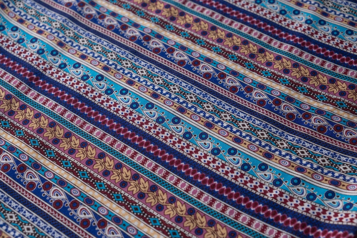Close-up of multicolor stripe pattern on blue rayon pants fabric.